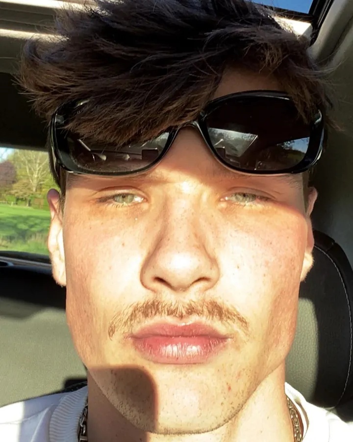 Homme en voiture, portant des lunettes de soleil, regardant vers l'appareil photo