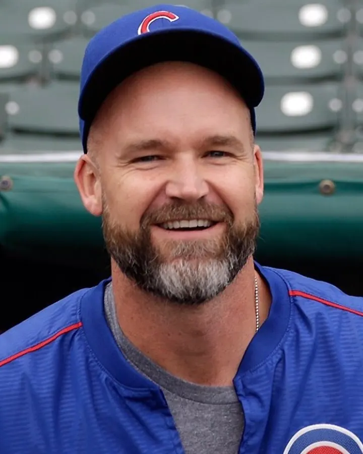 Homme souriant portant un bonnet bleu et une veste de sport bleue, en extérieur.