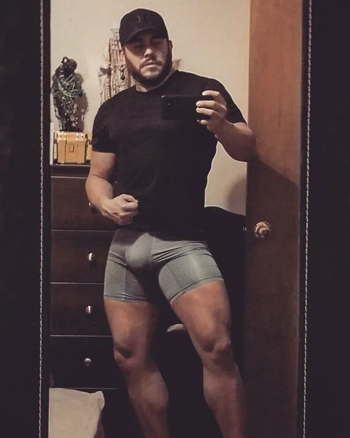 Homme torse nu, barbu, en t-shirt noir, prenant un selfie devant un miroir.