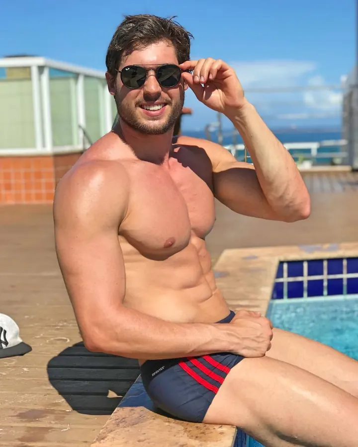 Homme européen torse nu, allongé sur un transat, dos à la caméra, muscles saillants