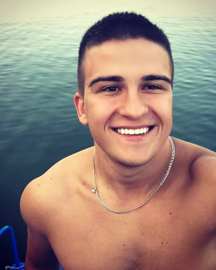 Homme européen torse nu, souriant, devant l'eau, chaîne argentée